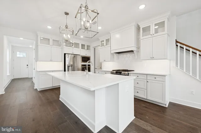 a open kitchen with stainless steel appliances granite countertop a white stove top oven and a chandelier
