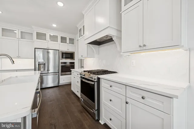 a kitchen with stainless steel appliances white cabinets and a refrigerator