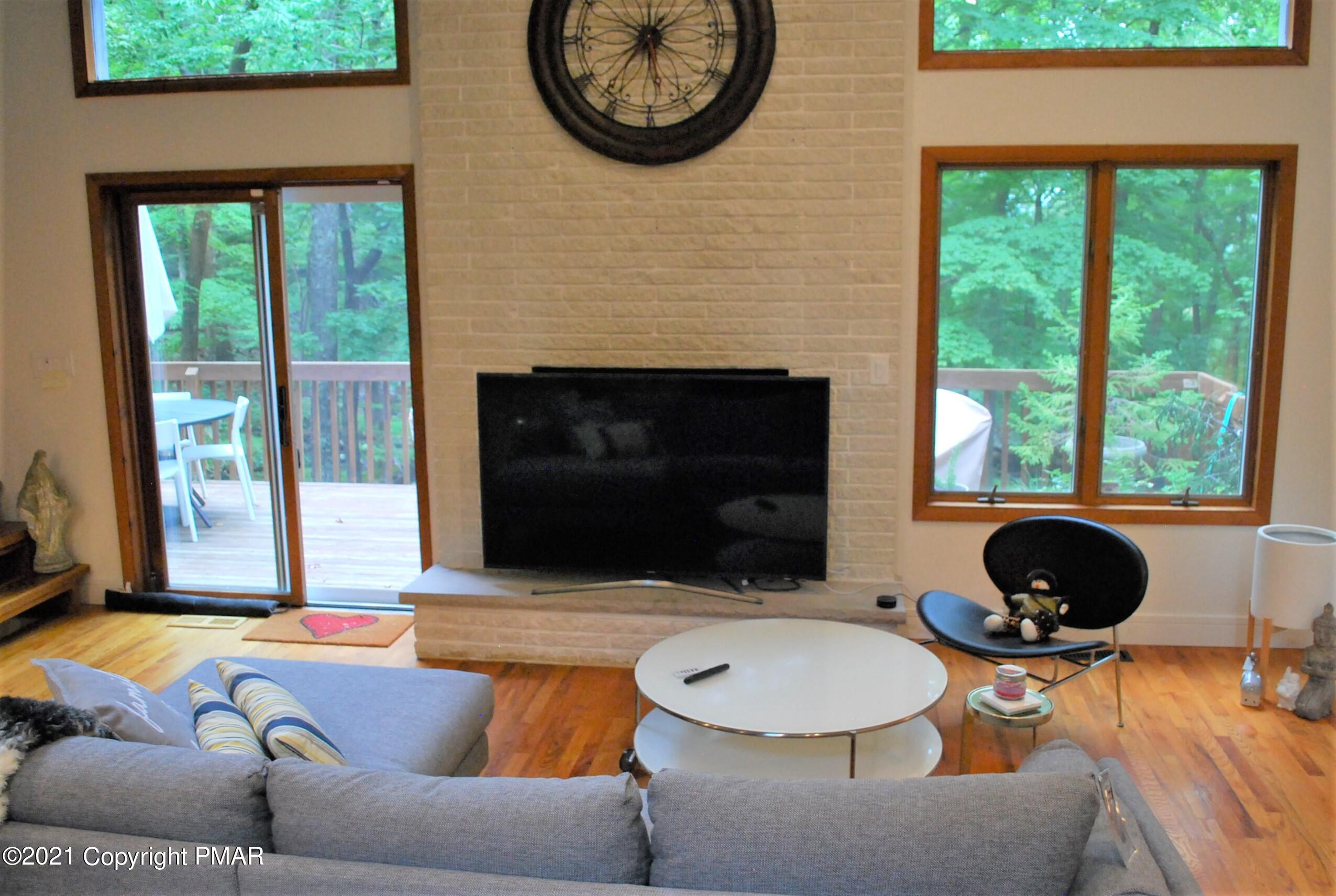 178 Edinburgh Road Bushkill, PA 18324 - Photo 6 of 54 a living room with a couch a fireplace a large window and potted plant