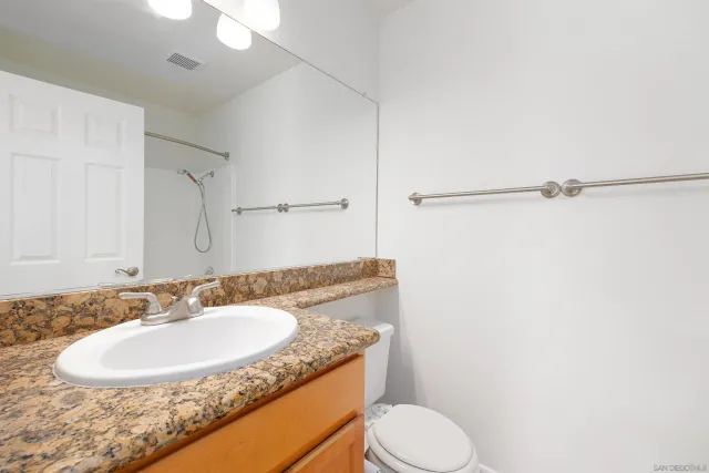 a bathroom with a granite countertop sink toilet and a mirror