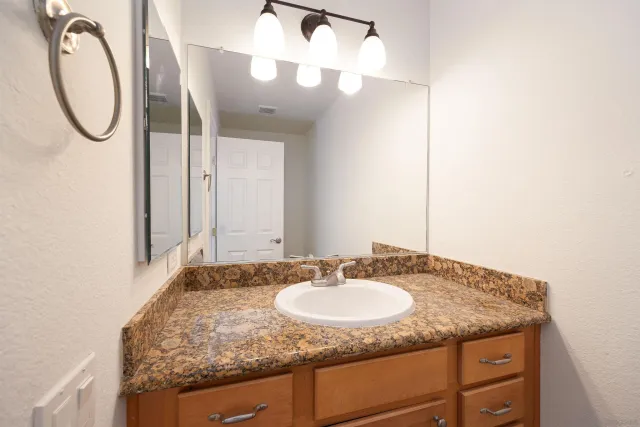 a bathroom with a granite countertop sink and a mirror