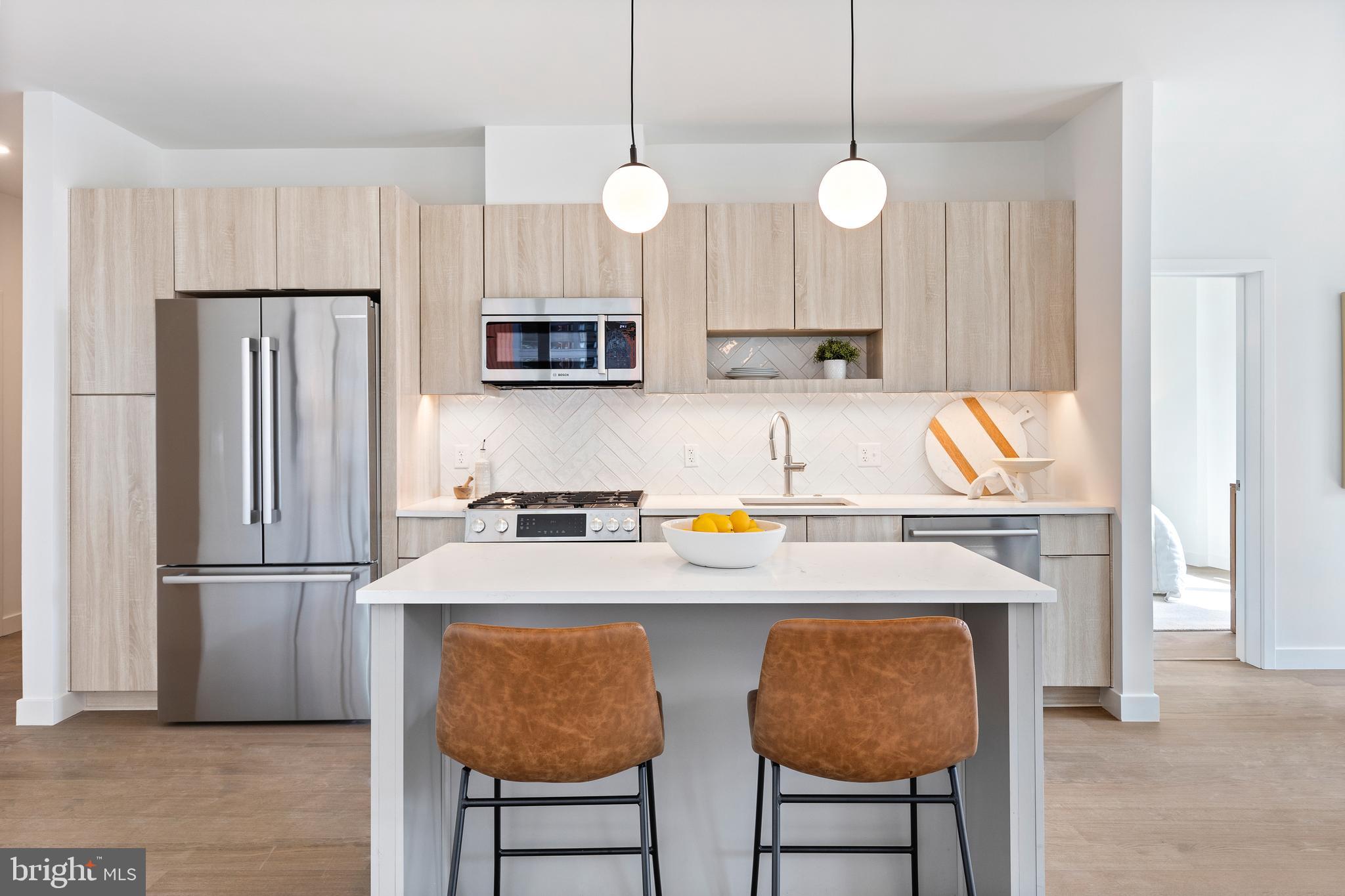 a kitchen with a refrigerator a microwave a sink and chairs