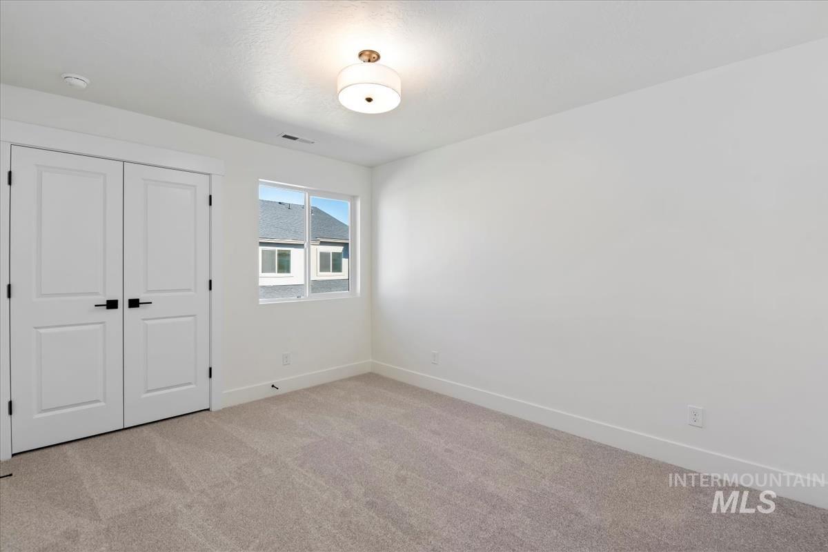 752 South Calhoun Lane Star, ID 83669 - Photo 25 of 45 Spacious room featuring neutral carpeting, white walls, and a contemporary flush-mount ceiling light