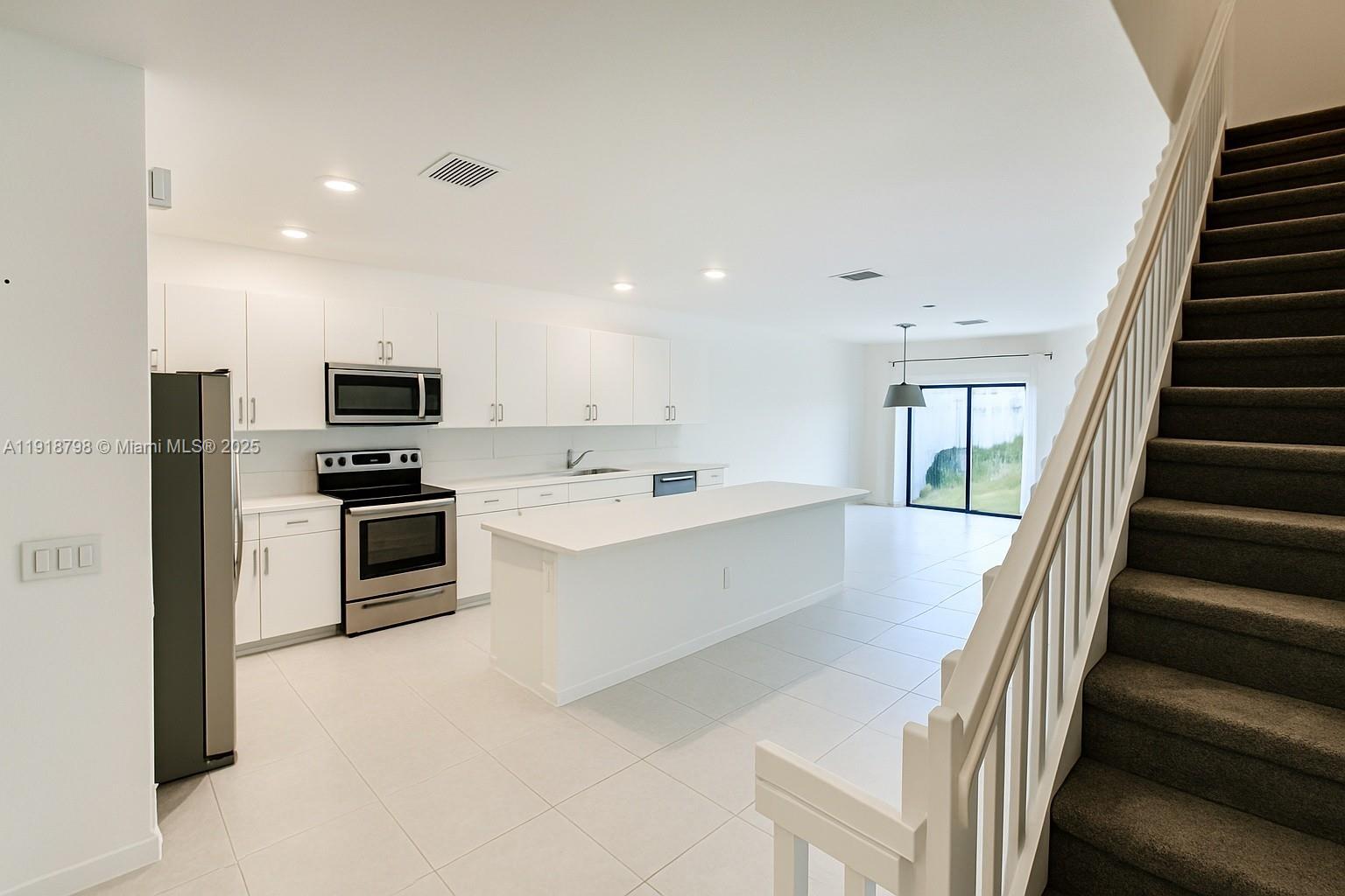 25564 Southwest 108th Avenue, Unit 25564 Homestead, FL 33032 - Photo 6 of 17 a large white kitchen with a refrigerator a stove top oven a sink and dishwasher