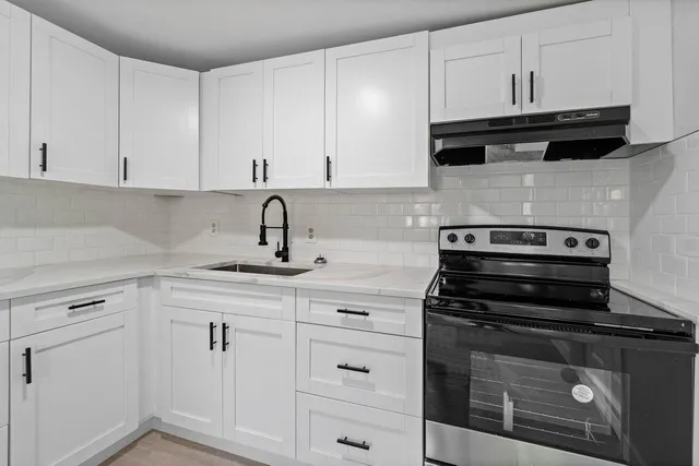 a kitchen with white cabinets and black appliances