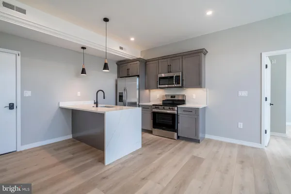 a kitchen with kitchen island stainless steel appliances a sink cabinets and a counter top space