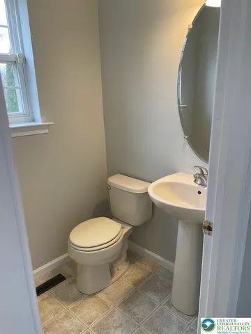 a white toilet sitting next to a bathroom sink and a mirror