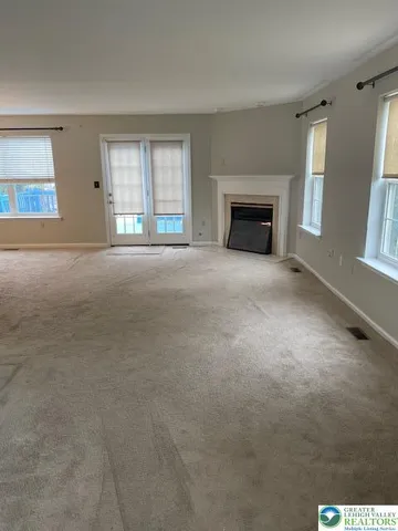 en empty room with windows and fireplace