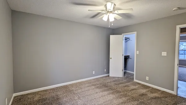 an empty room with closet and a chandelier fan