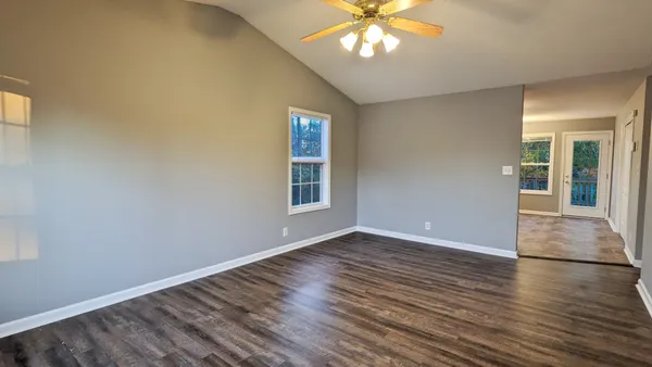 a view of an empty room with wooden floor and a window