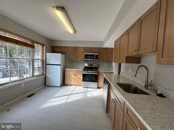 a kitchen with stainless steel appliances granite countertop a sink a stove a refrigerator cabinets and a sink