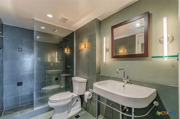 a bathroom with a sink toilet a mirror and shower