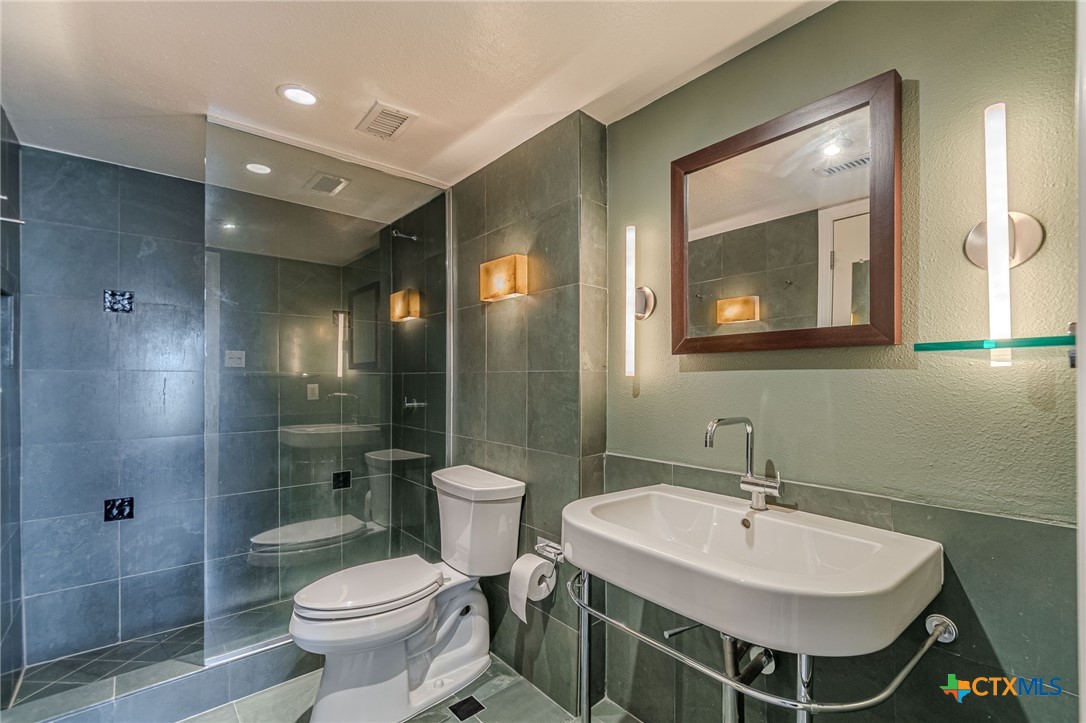 1122 Colorado Street, Unit 1409 Austin, TX 78701 - Photo 16 of 32 a bathroom with a sink toilet a mirror and shower