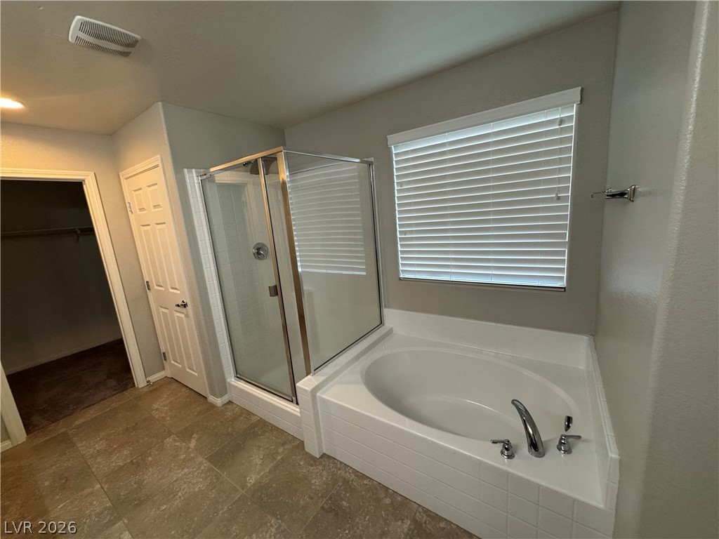 55 Canopus Ridge Way Las Vegas, NV 89183 - Photo 28 of 53 A glass-enclosed shower and adjacent soaking tub await in this bathroom with tile flooring.