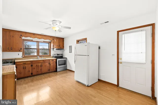 a kitchen with refrigerator a stove a sink and white cabinets with wooden floor