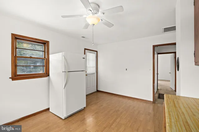 a view of empty room with wooden floor and ceiling fan