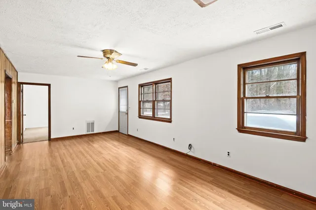 a view of an empty room with a window and wooden floor