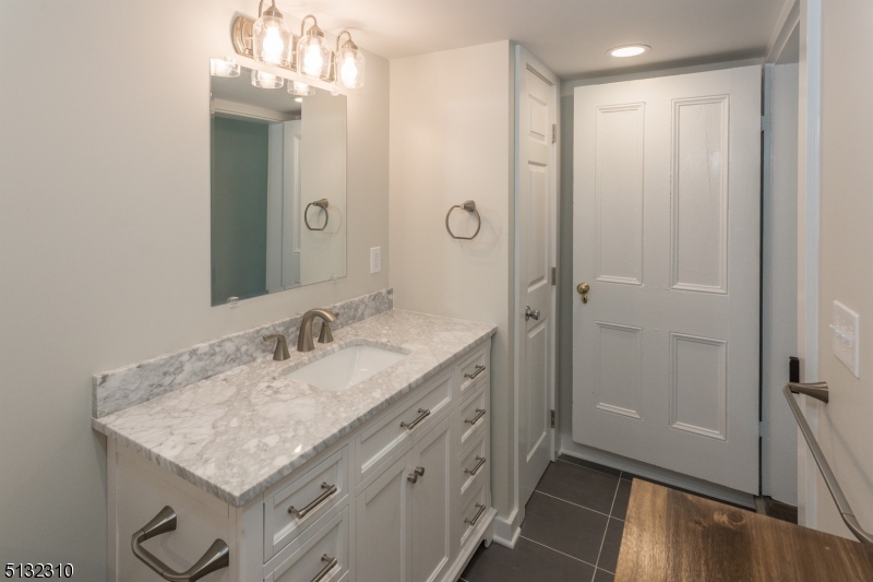 211 Washington Street, Unit 2 Hackettstown, NJ 07840 - Photo 22 of 30 a bathroom with a granite countertop sink a mirror and a shower