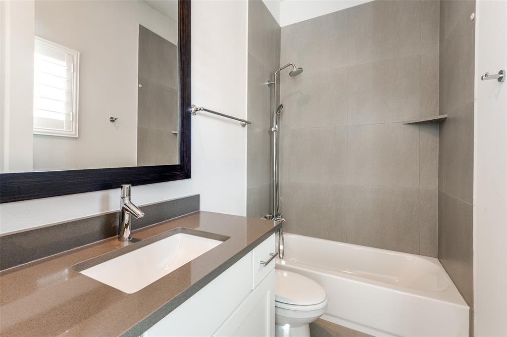 5421 Patterson Street Irving, TX 75039 - Photo 26 of 32 Bathroom vanity featuring an integrated rectangular sink with a chrome faucet, a dark-framed mirror, and a gray countertop