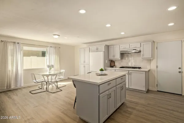 a kitchen with a sink stove and white cabinets with wooden floor