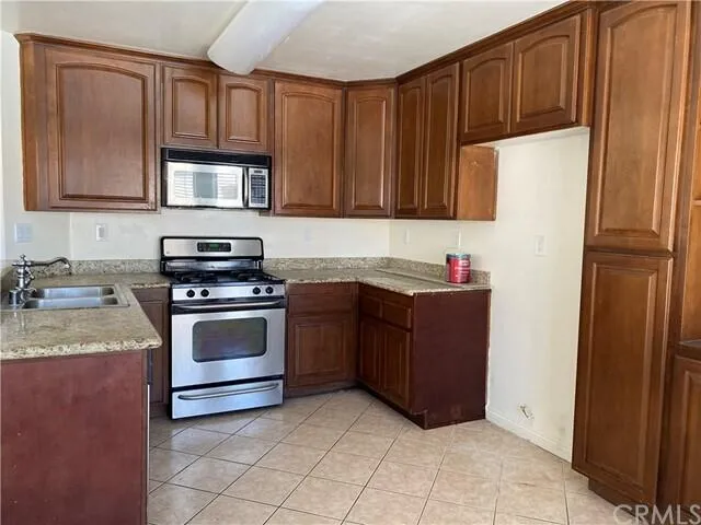 a kitchen with granite countertop a refrigerator a sink and wooden cabinets
