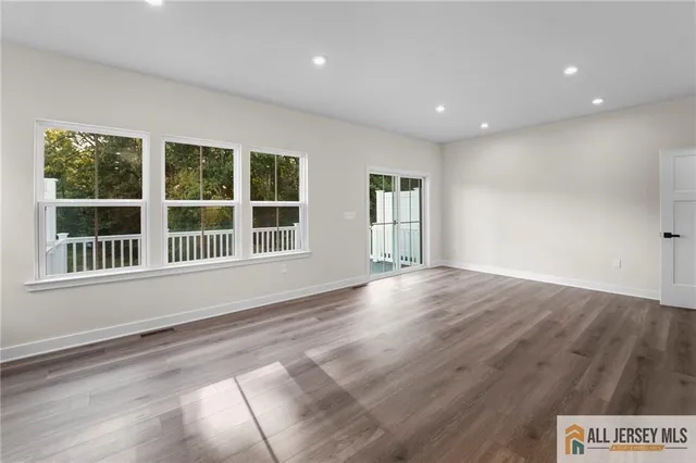 a view of an empty room with wooden floor and windows