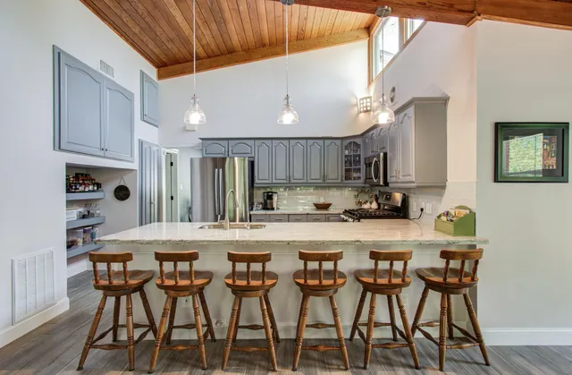 a kitchen with stainless steel appliances a table chairs refrigerator and cabinets