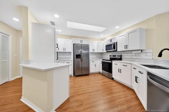 a view of an empty room with wooden floor and a ceiling fan