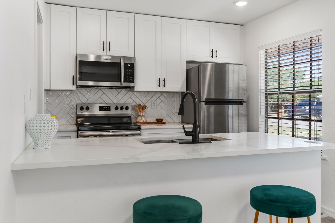 607 Magnolia Street Bastrop, TX 78602 - Photo 3 of 25 a kitchen with stainless steel appliances a refrigerator a stove a microwave and sink