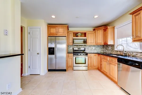 a kitchen with stainless steel appliances granite countertop a refrigerator and a stove top oven