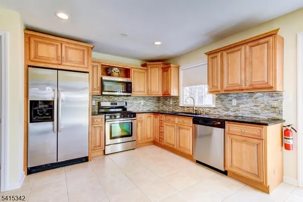 a kitchen with stainless steel appliances granite countertop a refrigerator and a stove top oven
