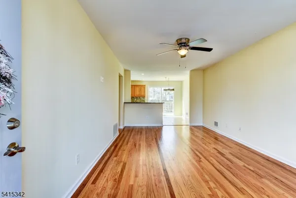 a view of a big room with wooden floor a ceiling fan and windows