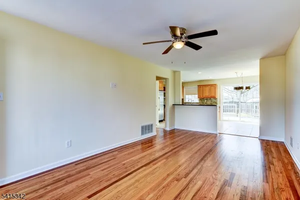 a view of empty room with wooden floor and ceiling fan