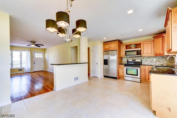 a kitchen with stainless steel appliances granite countertop a refrigerator a oven a sink with island and chairs