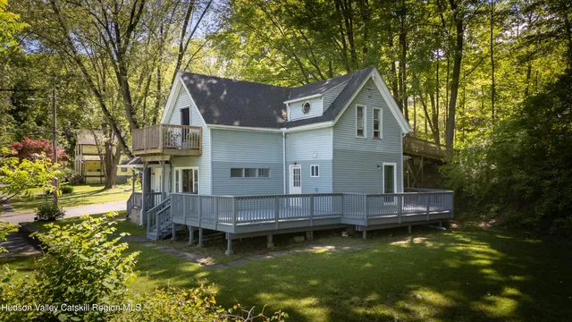 a view of house with a yard large trees and a wooden fence
