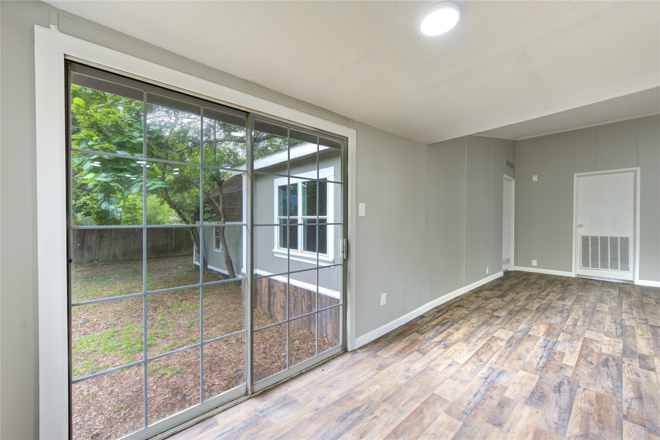 30226 Davis Street Magnolia, TX 77355 - Photo 15 of 50 Bright, open space with wood-style flooring and large sliding glass doors leading to a fenced backyard. Ideal for natural light and indoor-outdoor living.