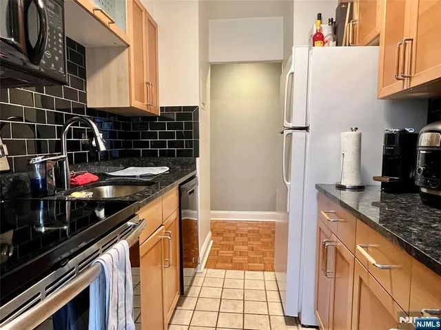 a kitchen with granite countertop a sink stove and refrigerator