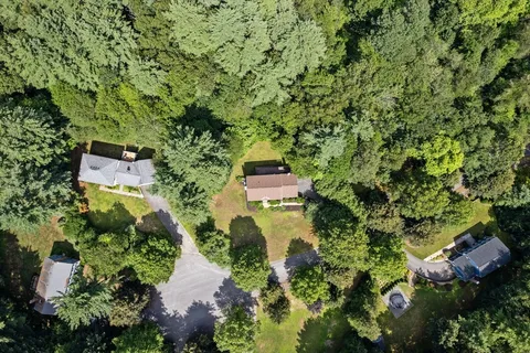 a aerial view of a house with a yard and large trees