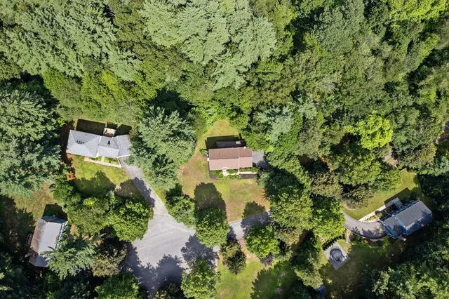 a aerial view of a house with a yard and large trees