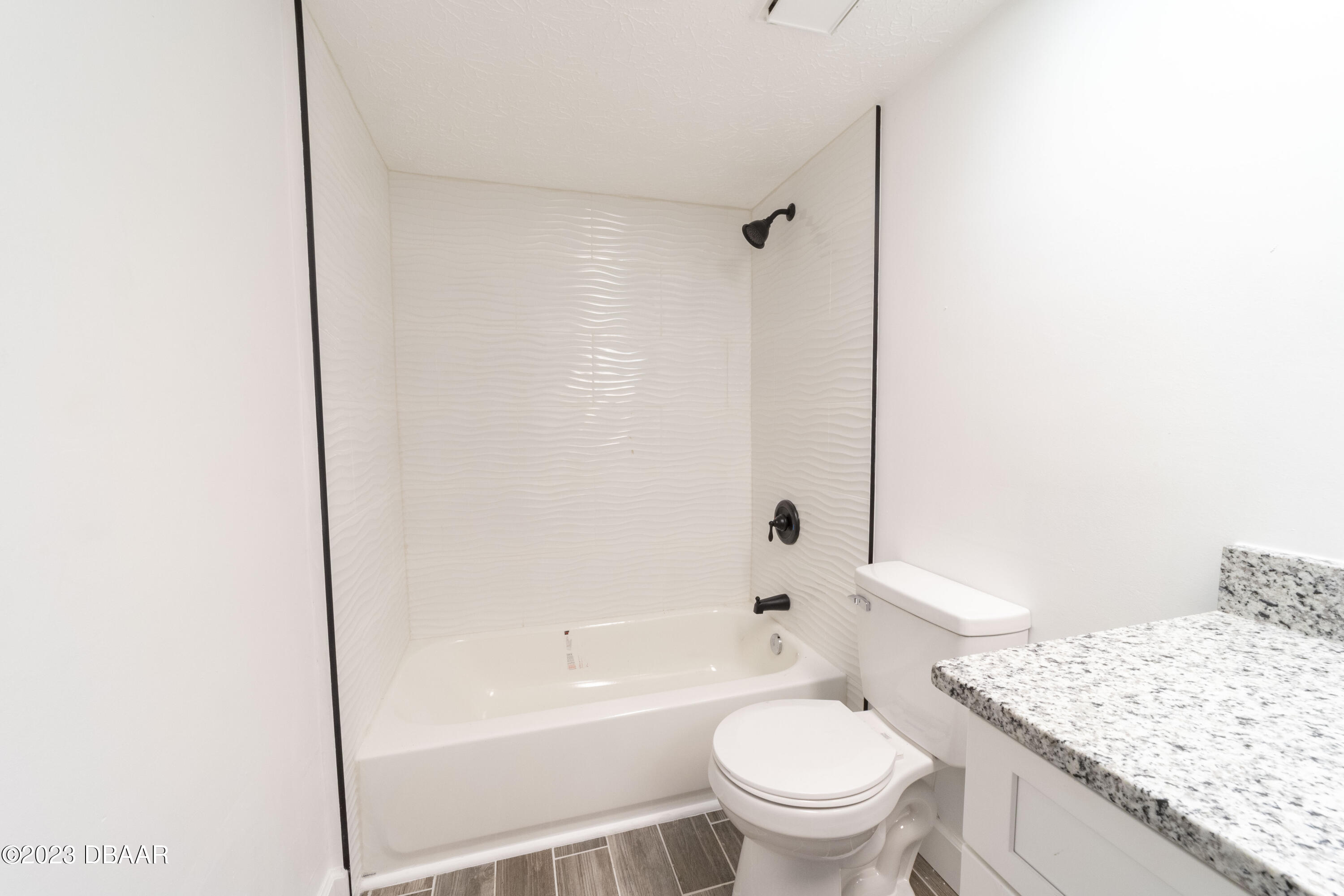 526 Live Oak Street, Unit 1050 Edgewater, FL 32132 - Photo 12 of 26 a bathroom with a granite countertop toilet a sink and a bathtub