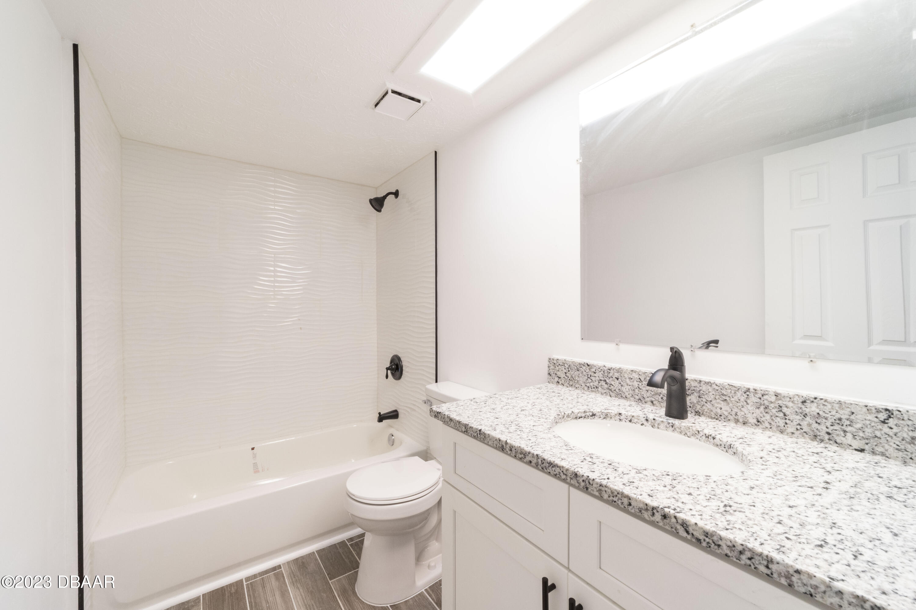 526 Live Oak Street, Unit 1050 Edgewater, FL 32132 - Photo 10 of 26 a bathroom with a granite countertop sink a toilet and bathtub