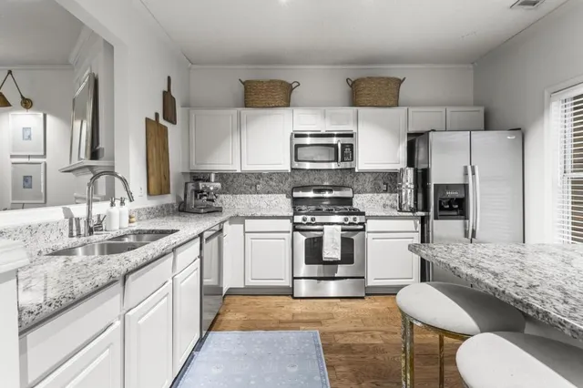 a kitchen with stainless steel appliances granite countertop a sink stove and refrigerator