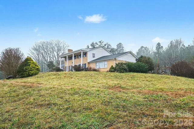 a front view of a house with a yard and mountain view in back