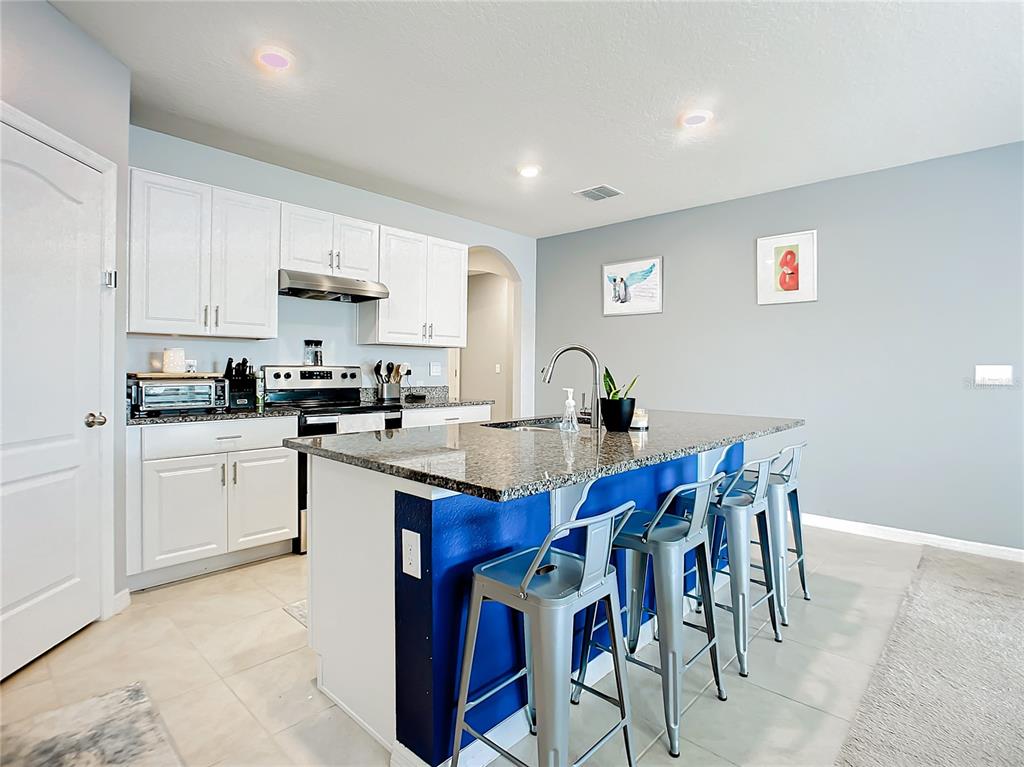 2607 Elmbrooke Way Edgewater, FL 32141 - Photo 7 of 52 a kitchen with stainless steel appliances a sink a stove a refrigerator cabinets and a dining table