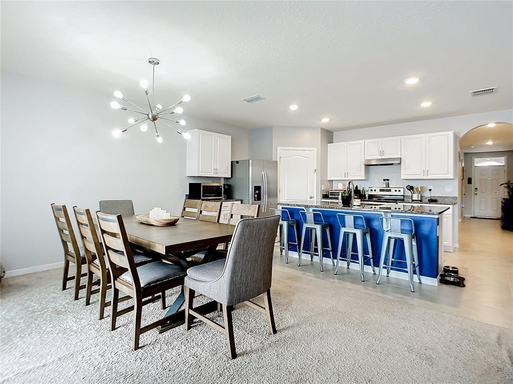 2607 Elmbrooke Way Edgewater, FL 32141 - Photo 10 of 52 a open dining room with stainless steel appliances kitchen island granite countertop a dining table chairs and a refrigerator