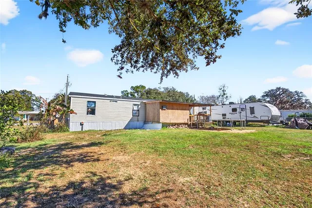 a view of a house with a yard and a large tree