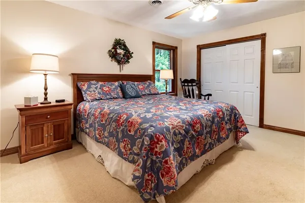 a large bed sitting in a bedroom next to a lamp on dresser and a chandelier