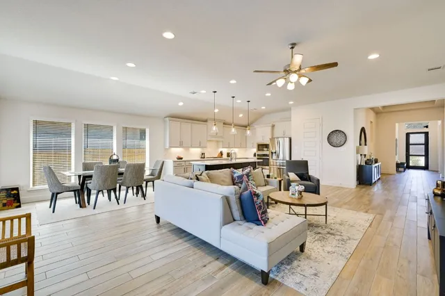 a living room with furniture kitchen view and a wooden floor