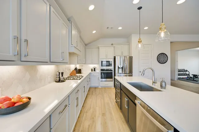 a kitchen with stainless steel appliances granite countertop a sink a stove and a refrigerator