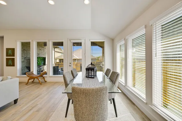 a dining room with wooden floor and large windows